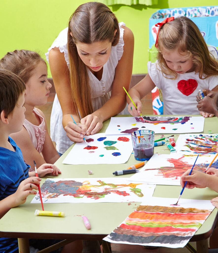 Nursery,Teacher,Painting,With,Children,And,Brushes,And,Watercolor,In
